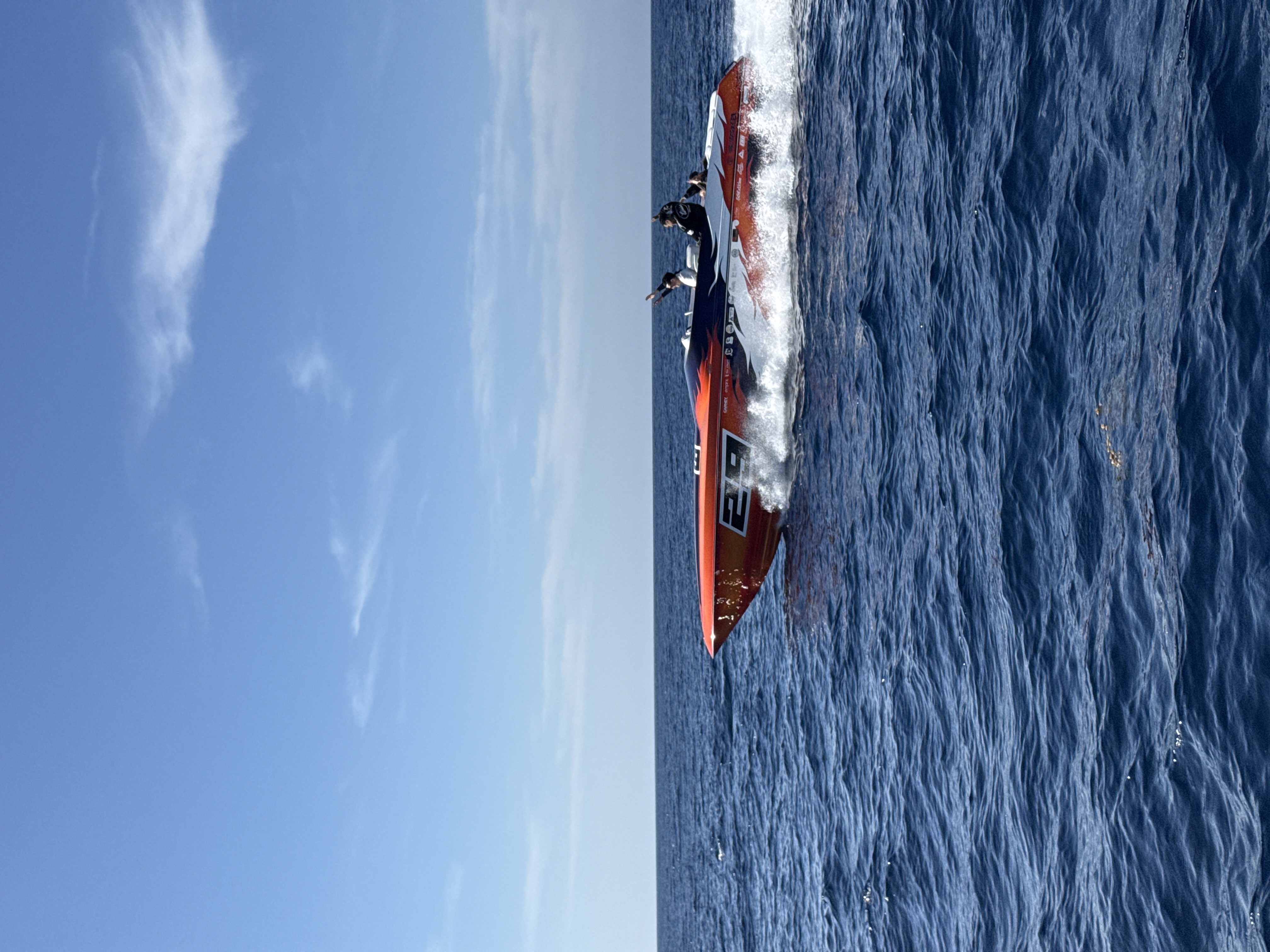 Orange and purple race boat #29 at full speed, water spray flying