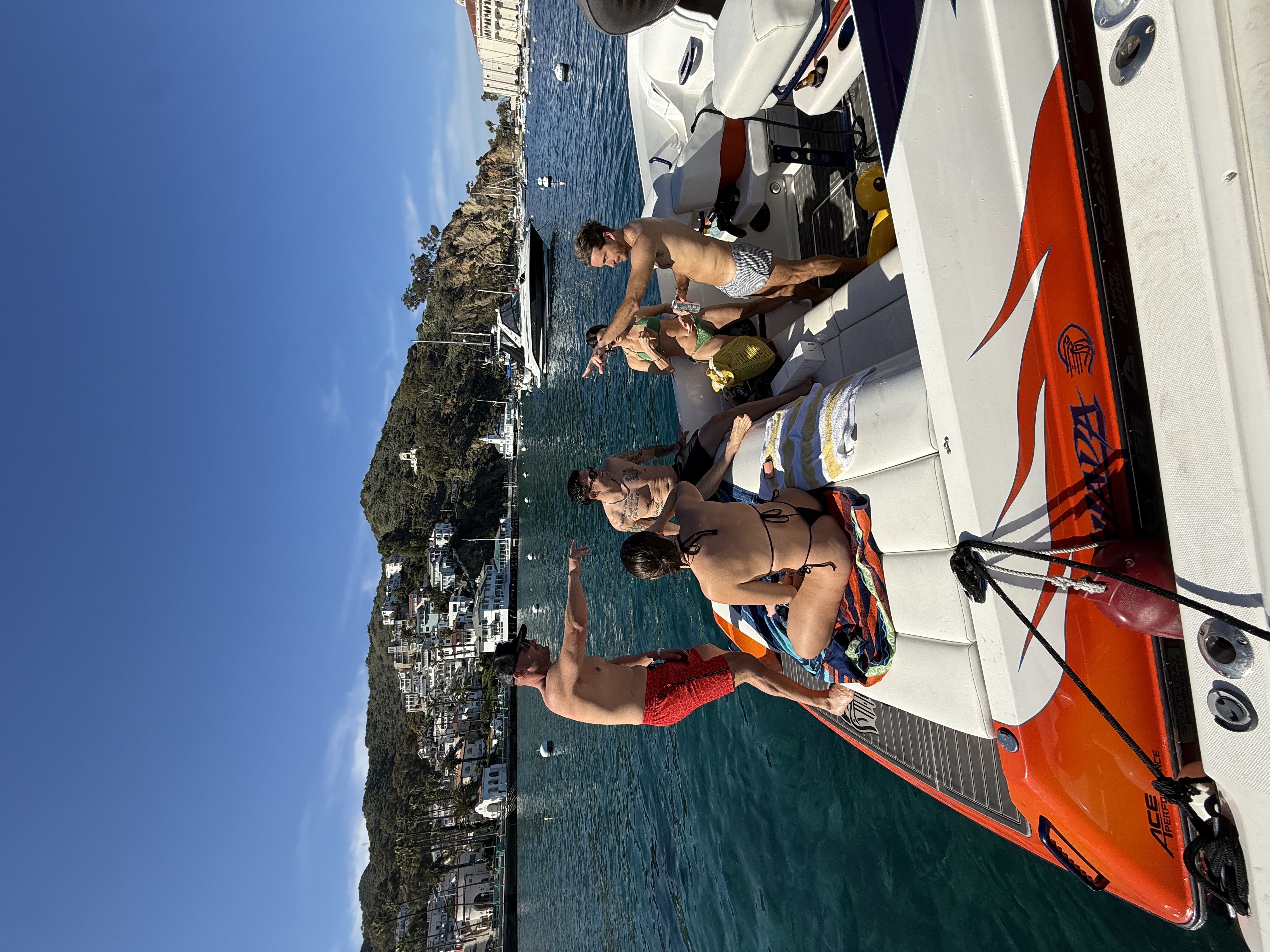 Group of friends hanging out on race boat #29 in Avalon Harbor with Catalina Casino behind