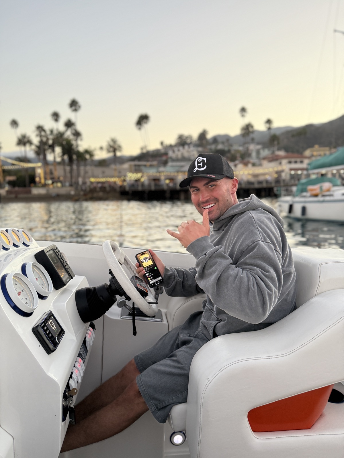 Captain at the helm of a boat at dusk with Avalon Harbor glowing behind