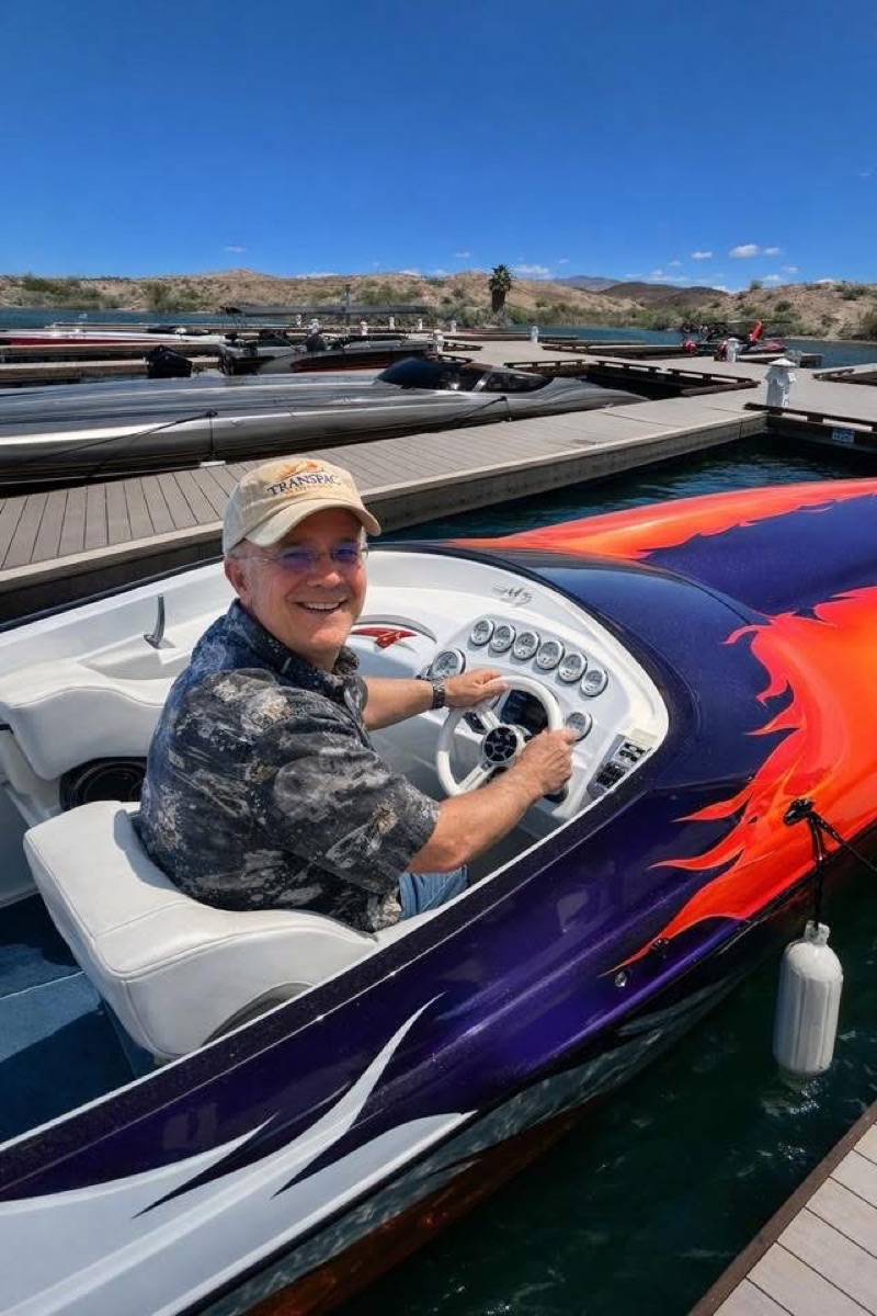 Man smiling at the helm of race boat #29 at the marina