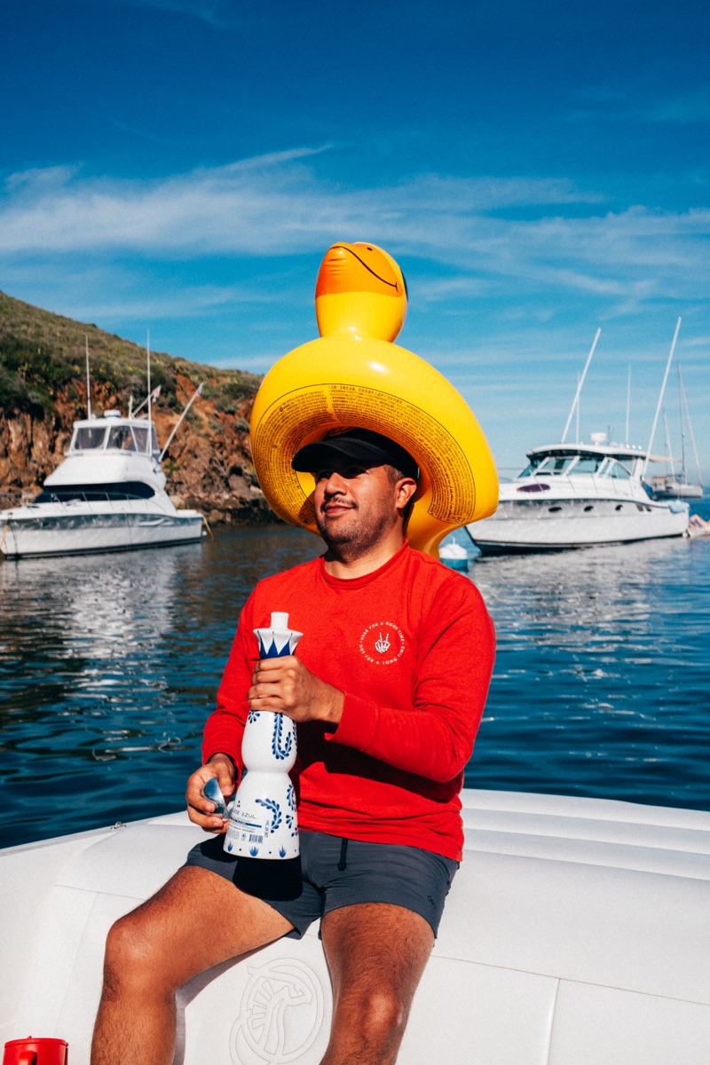 Guy in yellow rubber duck hat holding Clase Azul tequila in Avalon Harbor